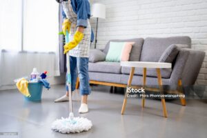 Young woman holding a floor wiper and wiping floor, keeping the daily home hygiene and doing housework.